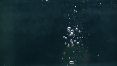 Zitrone-Fällt-Mit-Blasen-Auf-Dunklem-Hintergrund-Ins-Wasser.
